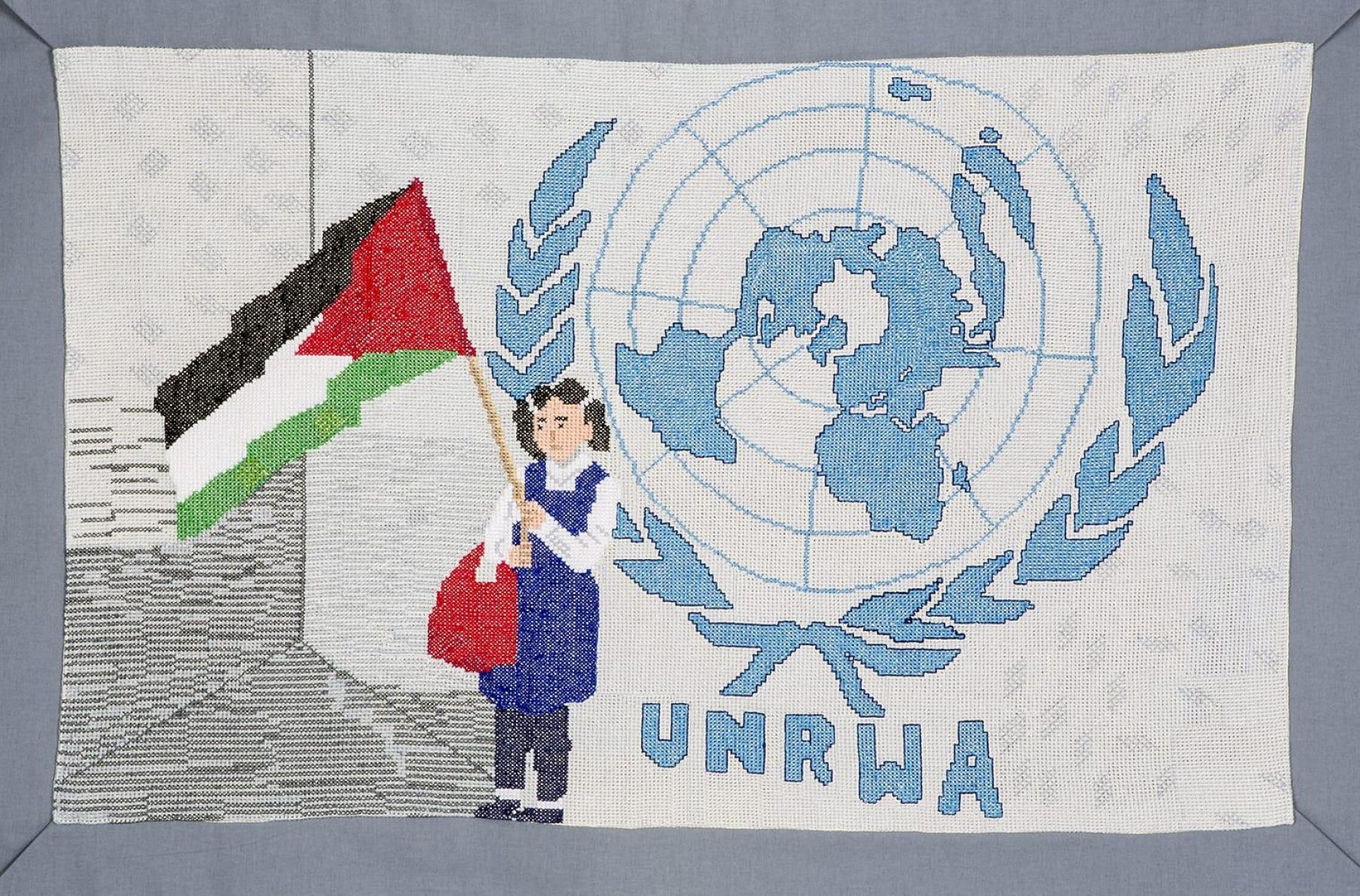 Image of tapestry with young girl holding Palestinian flag in front of wall with UNRWA logo