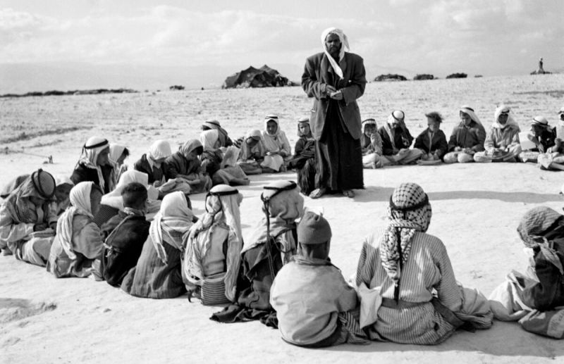 Bedouin children sitting outside around an adult.